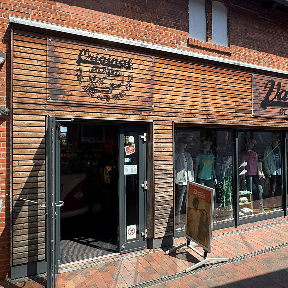 vocc1000x1000 - Windsport Fehmarn Fassade eines Van One Classics Shops mit Holzverkleidung, Schaufensterpuppen und einem Hinweisschild.