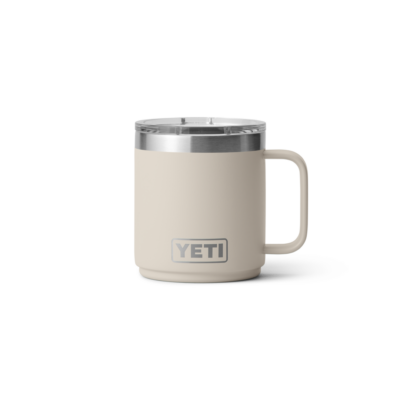 Ein beiger YETI Isolierbecher aus Edelstahl mit Deckel und Henkel auf weißem Hintergrund.