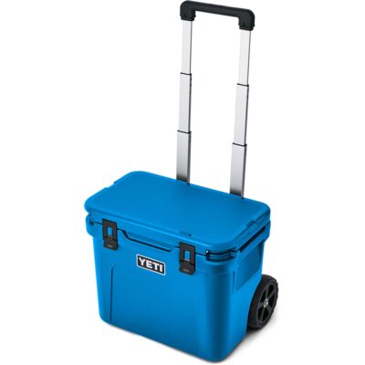 Blaue YETI Roadie Kühlbox mit ausziehbarem Teleskopgriff und robusten Rollen vor weißem Hintergrund