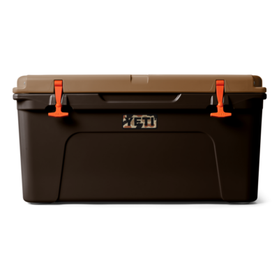 Dunkelbraune YETI Tundra Kühlbox mit beigem Deckel und leuchtend orangen Verschlüssen vor weißem Hintergrund.