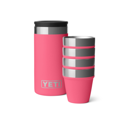Ein pinker YETI Isolierbehälter mit vier gestapelten, passenden Bechern auf weißem Hintergrund.