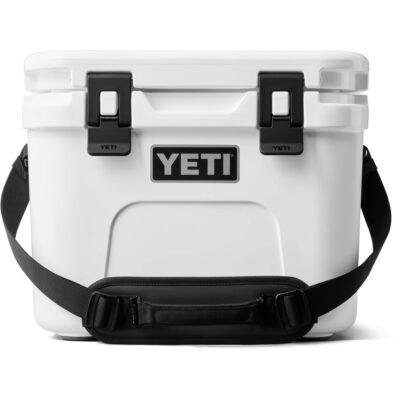 Weiße Yeti Kühlbox mit schwarzem Tragegurt und zwei schwarzen Verschlüssen vor weißem Hintergrund.