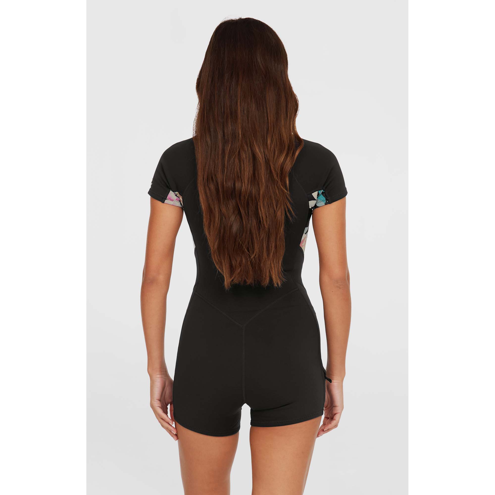 O'Neill Bahia Neopren-Shorty Rückansicht - Windsport Fehmarn Frau von hinten in einem schwarzen O'Neill Bahia Kurzarm-Neoprenanzug mit floralen Akzenten an den Ärmeln