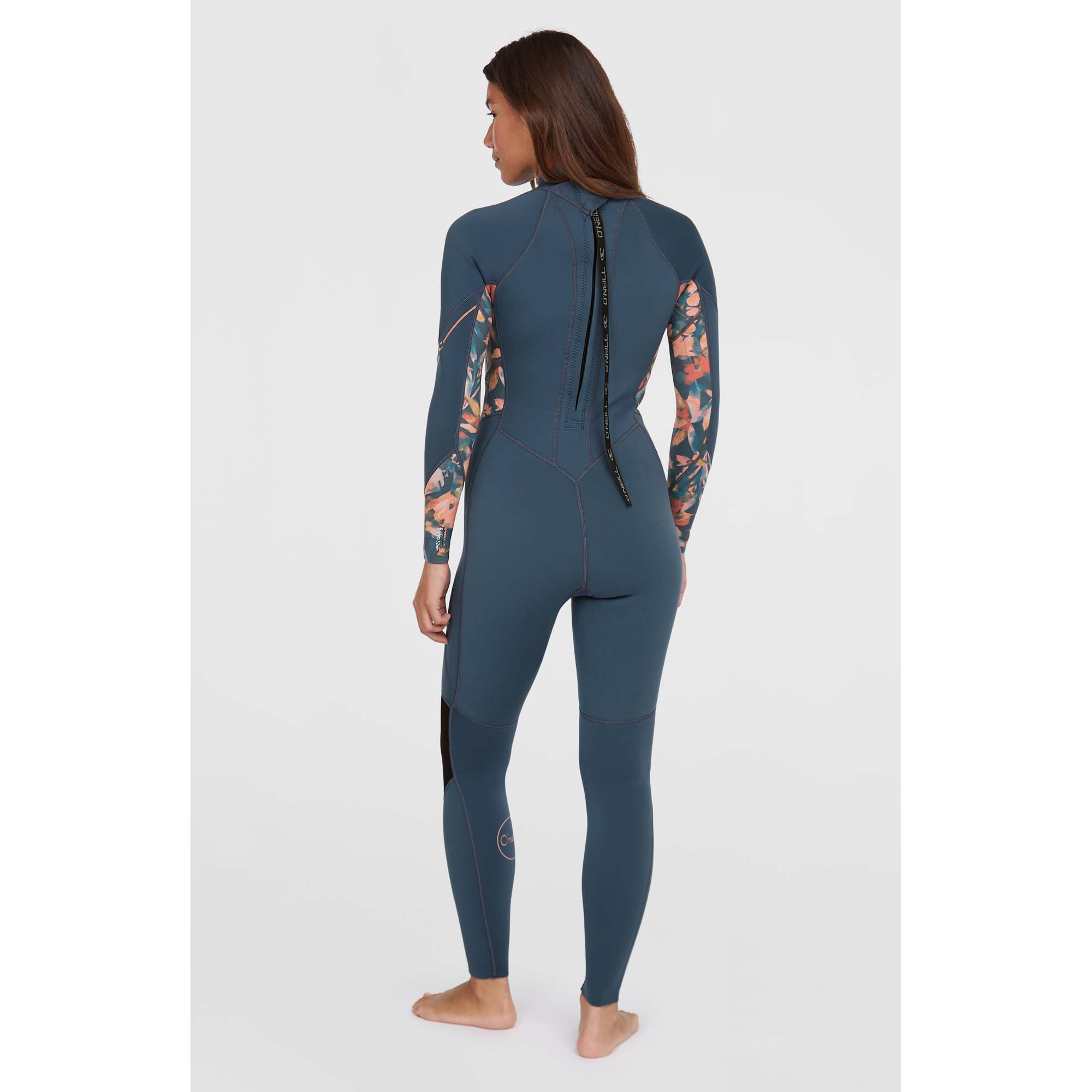 O'Neill Damen Bahia Neoprenanzug - Windsport Fehmarn Rückansicht einer Frau in einem blauen O'Neill Bahia 3/2mm Neoprenanzug mit floralen Ärmelmustern vor hellem Hintergrund.