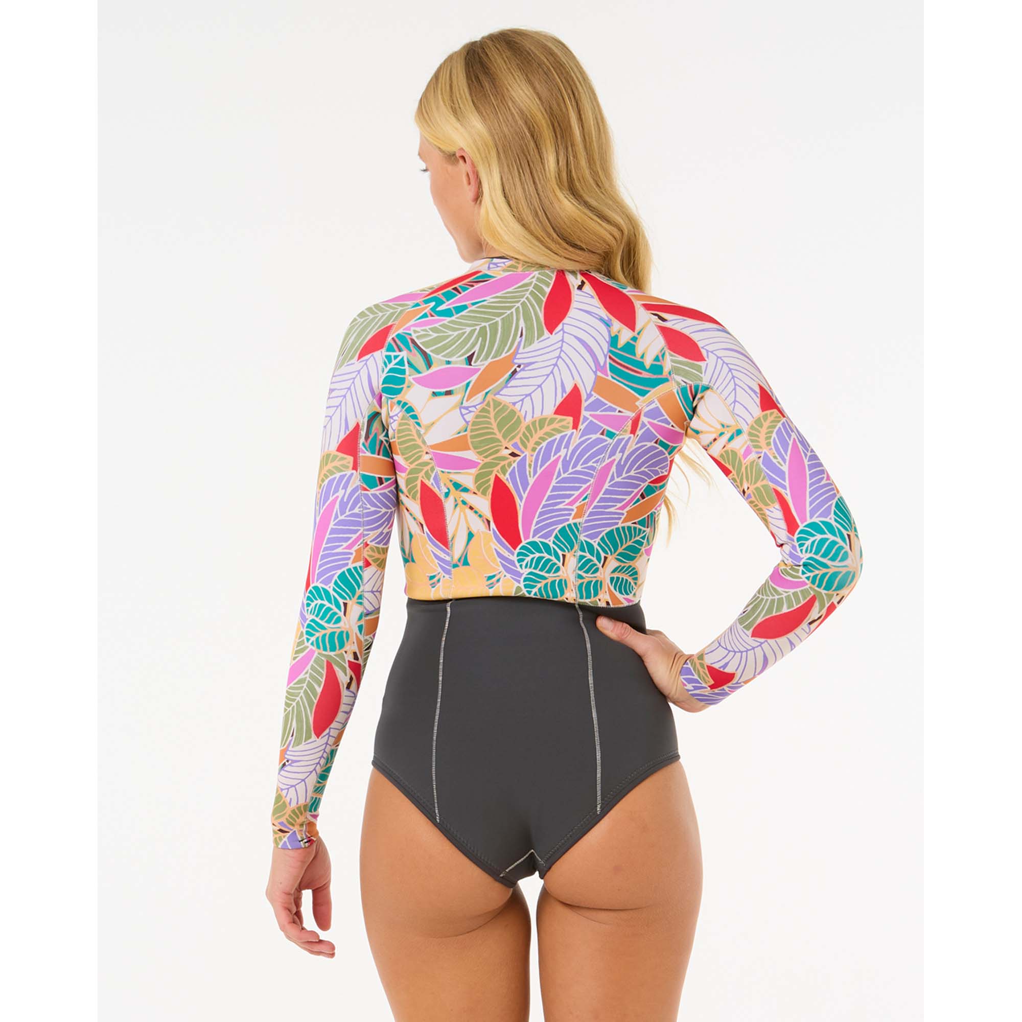 Buntes Surf-Oberteil mit langen Ärmeln - Windsport Fehmarn Rückansicht einer Frau in einem langärmeligen Surf-Oberteil mit buntem Blattmuster und dunkelgrauem Bikini-Unterteil