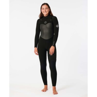 Eine Frau in einem schwarzen Rip Curl Flashbomb Neoprenanzug lächelt in die Kamera vor weißem Hintergrund.