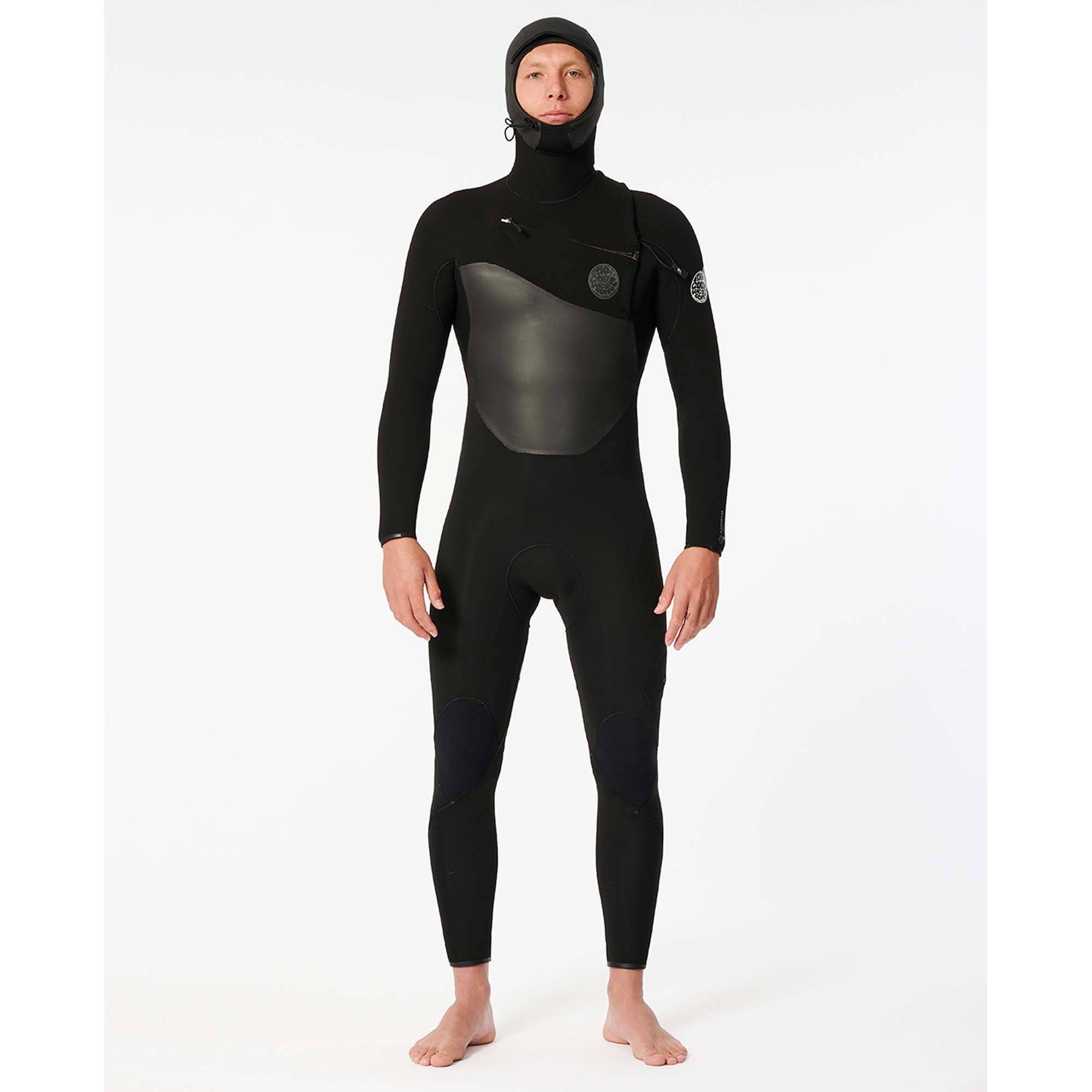 Rip Curl Flashbomb Neoprenanzug - Windsport Fehmarn Ein Surfer trägt einen schwarzen Rip Curl Flashbomb Neoprenanzug mit integrierter Kapuze vor weißem Hintergrund.