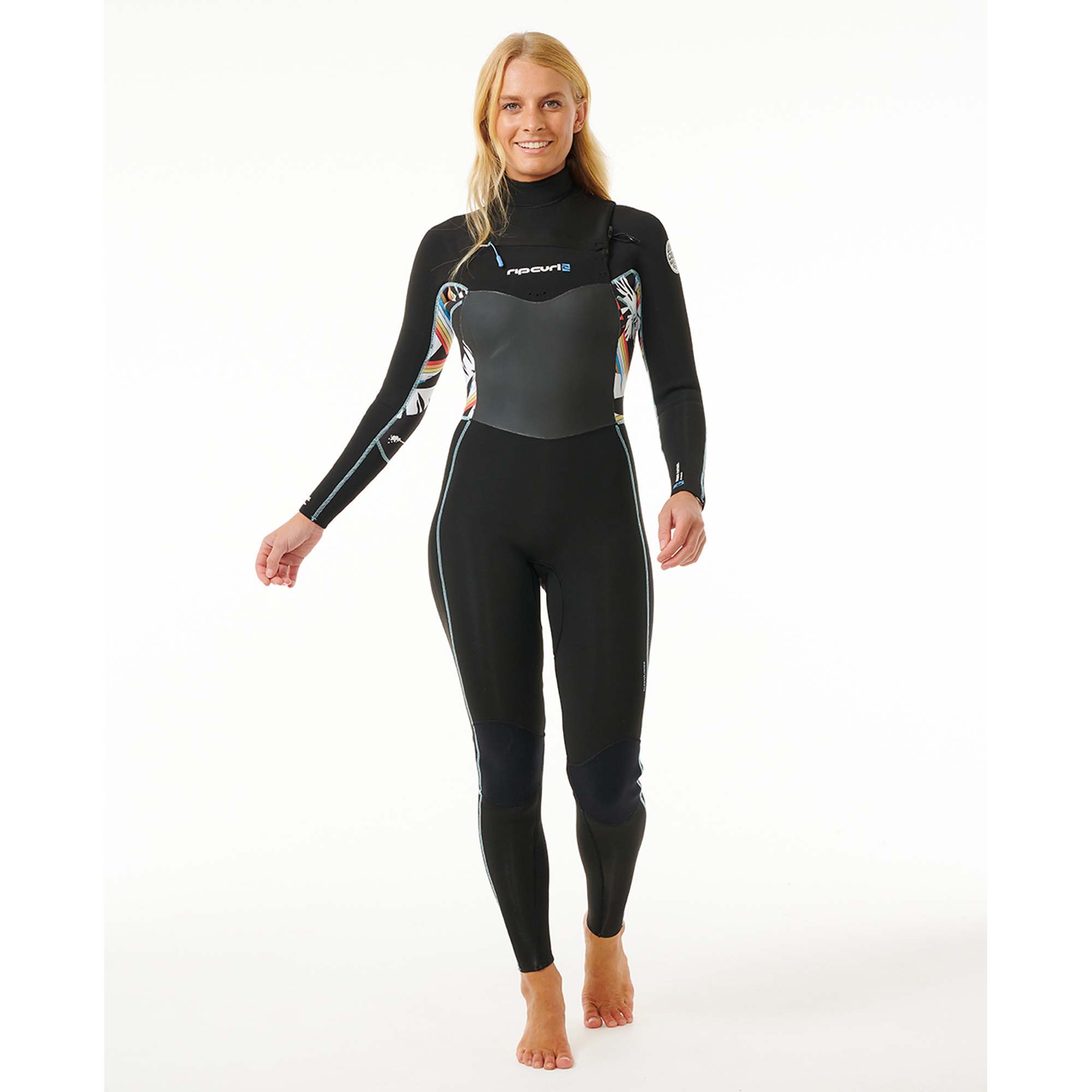 Rip Curl Damen-Neoprenanzug - Windsport Fehmarn Eine lächelnde Frau trägt einen schwarzen Rip Curl Neoprenanzug mit bunten grafischen Details an den Ärmeln vor weißem Grund.