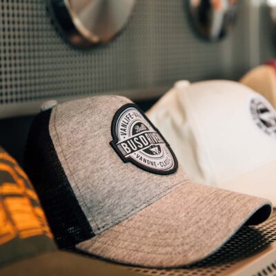Mehrere Baseball-Caps mit Vanlife- und Bulli-Logos in einem Regal ausgestellt