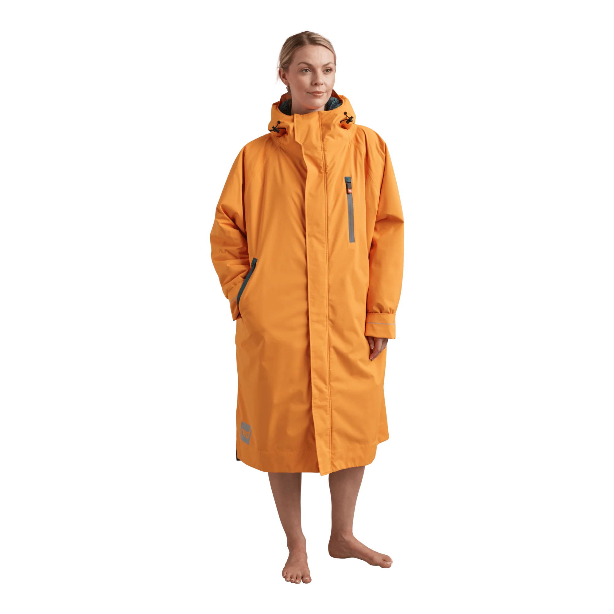 Mevo Pro Parka Bitter Orange - Windsport Fehmarn Eine Frau trägt den leuchtend orangen Mevo Pro Parka vor weißem Hintergrund.