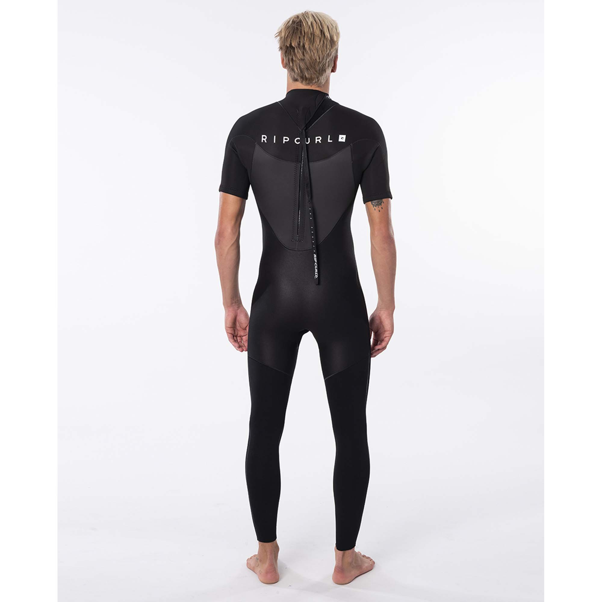 Rip Curl Herren Wetsuit Rückansicht - Windsport Fehmarn Rückansicht eines blonden Mannes im schwarzen Rip Curl Kurzarm-Wetsuit vor weißem Hintergrund.